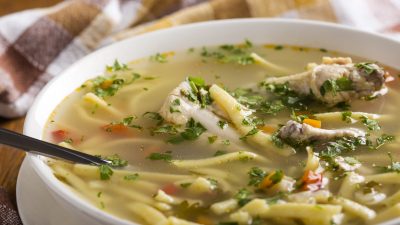 Chicken noodel soup with spoon and herbs